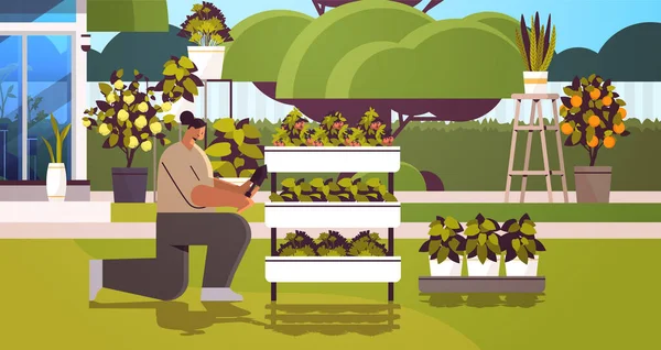 Femme jardinier avec pelle prenant soin des plantes en pot à la serre arrière-cour ou jardin à la maison horizontal — Image vectorielle