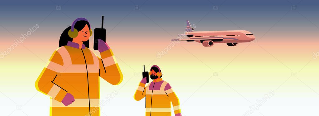 airport workers marshallers communicating over walkie-talkie with air traffic control while airplane flying in sky professional airport staff