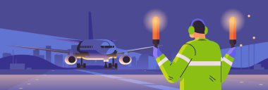 aviation marshaller supervisor with light sticks near aircraft air traffic controller airline worker in signal vest professional airport staff concept night cityscape background horizontal portrait
