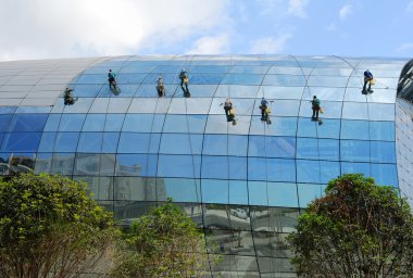 Industrial mountaineering workers wash windows of a high-rise building clipart