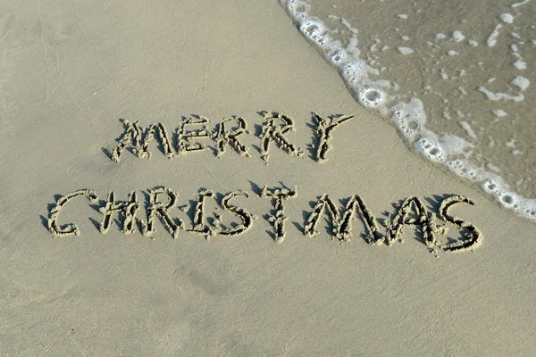Merry Christmas handwritten in sand on a beautiful beach — Stock Photo, Image