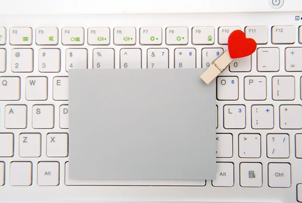 Laptop keyboard with small red hearts clothes pegs and sticky note — Stock Photo, Image