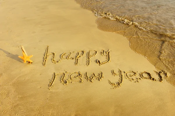 Feliz ano novo escrito na areia — Fotografia de Stock