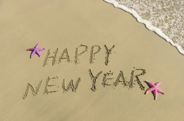 Feliz año nuevo escrito en la arena — Foto de Stock