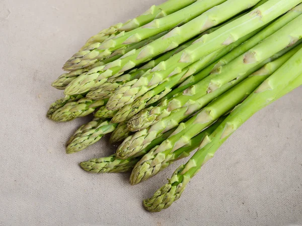 Brotos de espargos verdes frescos que colocam no fundo de bambu — Fotografia de Stock