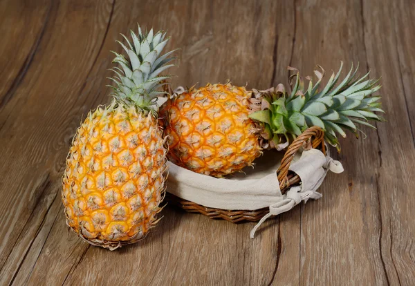 Ahşap arkaplanda sepetli iki ananas. — Stok fotoğraf