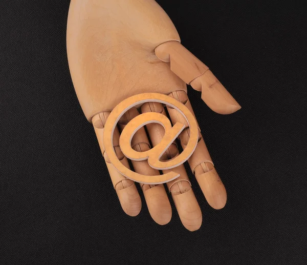 Wooden mannequin's hands, holding email symbols — Stock Photo, Image