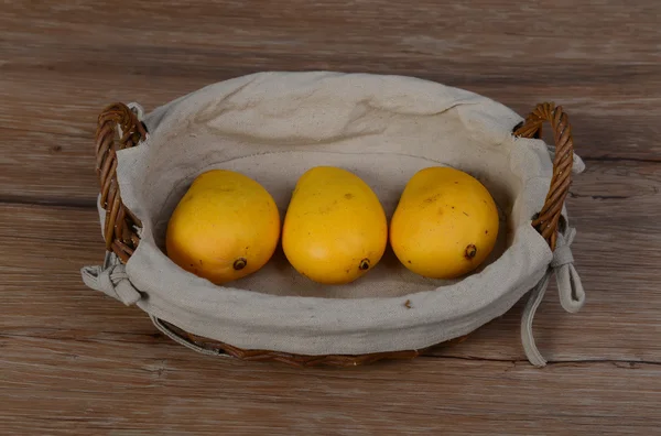 Три манго в коричневой плетеной корзине изолированы крупным планом — стоковое фото