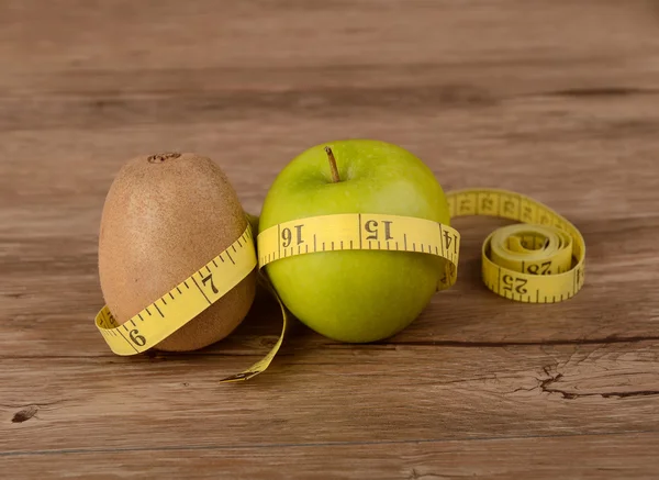 Concepto de dieta, kiwi con manzana verde y cinta métrica —  Fotos de Stock