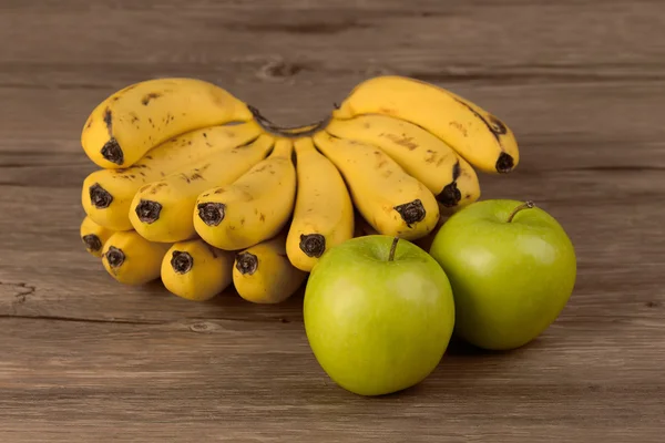 Banane und Apfel isoliert auf Holzgrund — Stockfoto