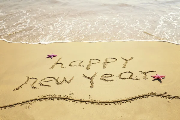 Feliz año nuevo mensaje en la playa de arena — Foto de Stock