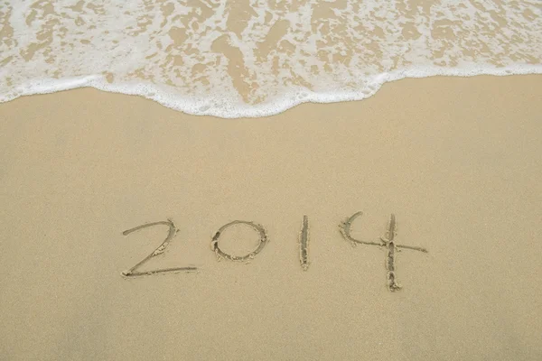 Año 2014 escrito a mano en la arena blanca frente al mar — Foto de Stock