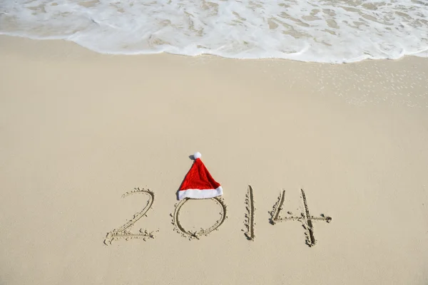 2014 med santa snögubbe på havet sandstrand med våg — Stockfoto