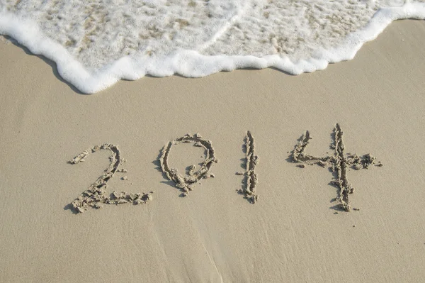 Year 2014 hand written on the white sand in front of the sea Stock Picture