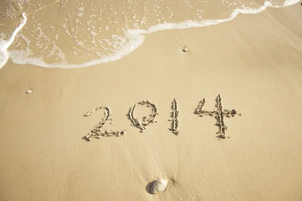 Ano 2014 mão escrita na areia branca em frente ao mar — Fotografia de Stock