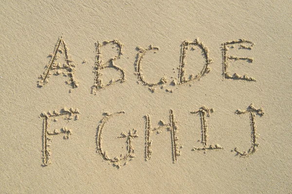 Alphabet-Buchstaben handgeschrieben im Sand am Strand — Stockfoto