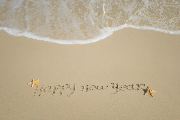 С Новым годом, написанным на песке — стоковое фото