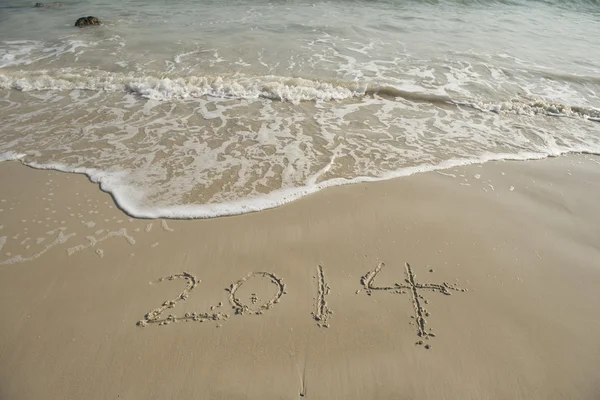 Jahr 2014 handgeschrieben auf dem weißen Sand vor dem Meer — Stockfoto