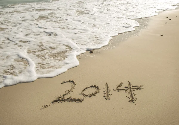 Jahr 2014 handgeschrieben auf dem weißen Sand vor dem Meer — Stockfoto