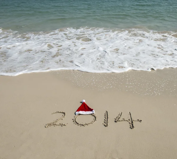 Año 2014 escrito a mano en la arena blanca frente al mar — Foto de Stock