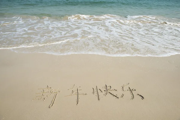 Chinesische Kalligraphie für ein frohes neues Jahr in den Sand geschrieben — Stockfoto