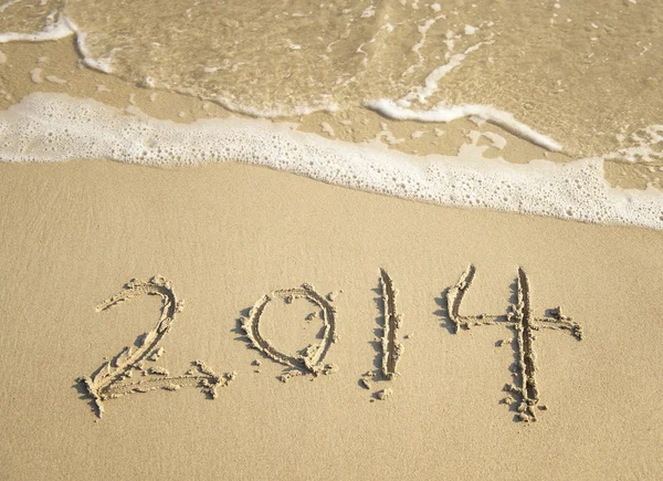 Year 2014 hand written on the white sand in front of the sea Stock Image