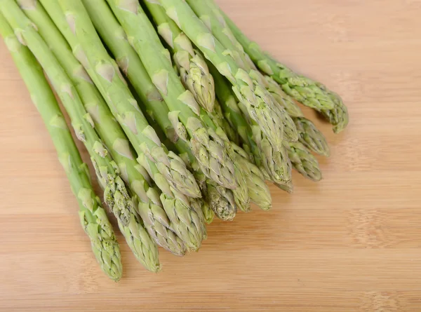 Brotos de espargos verdes frescos que colocam no fundo de bambu — Fotografia de Stock