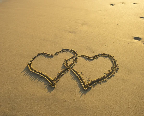 Iki kalp sahilde kum çizilmiş Telifsiz Stok Fotoğraflar