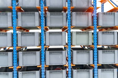 Otomatik deponun hücrelerindeki plastik kutular. Metal inşaat deposu rafları