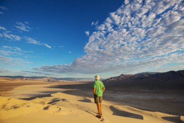 Çöldeki kum tepelerinin arasında bir yürüyüşçü