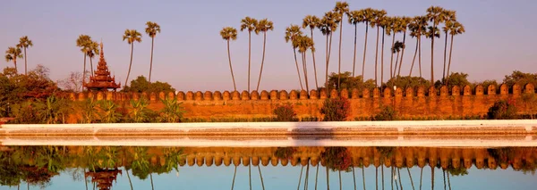 Ancient brown brick Palace wall with reflection in the canal surrounding the Mandalay palace located in Mandalay, Burma (Myanmar) at sunrise