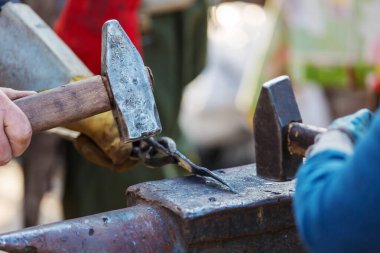 Demirci, erimiş metali elle örs üzerinde dövüyor.