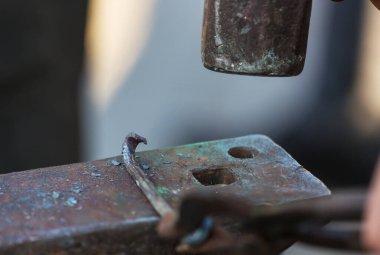 Demirci, erimiş metali elle örs üzerinde dövüyor.