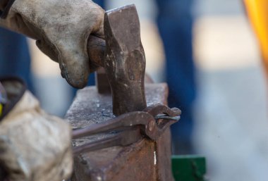 Demirci, erimiş metali elle örs üzerinde dövüyor.