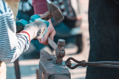 Demirci, erimiş metali elle örs üzerinde dövüyor.