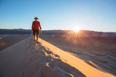 Kum çölünde bir yürüyüşçü. Gün doğumu zamanı.