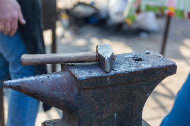 Demirci, erimiş metali elle örs üzerinde dövüyor.