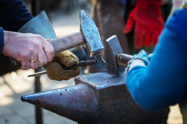 Demirci, erimiş metali elle örs üzerinde dövüyor.