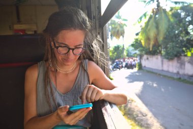 Sri Lanka 'nın dağlık bölgelerindeki çay tarlaları arasında Ella' dan Kandy 'ye tren yolculuğunun tadını çıkaran genç bir kadın.