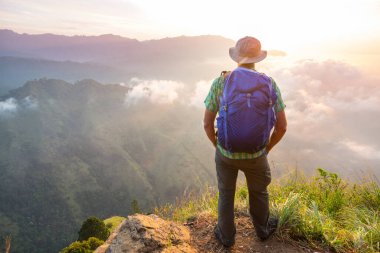 Bir turist, dağlık arazileri gözetliyor.