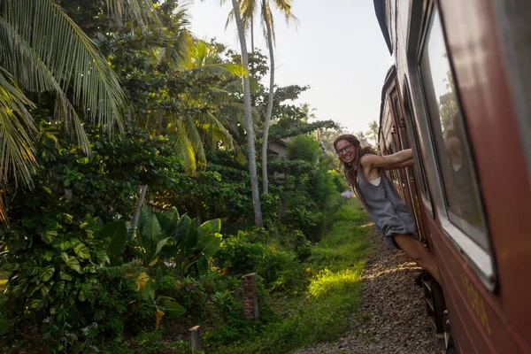 Sri Lanka 'nın dağlık bölgelerindeki çay tarlaları arasında Ella' dan Kandy 'ye tren yolculuğunun tadını çıkaran genç bir kadın.