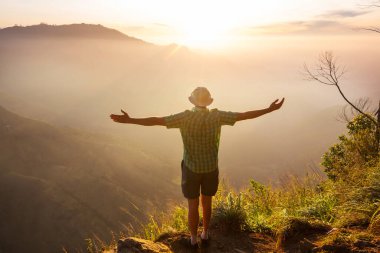 Bir turist, dağlık arazileri gözetliyor.
