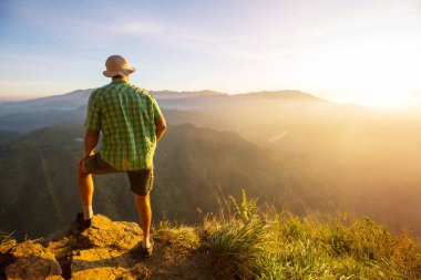 Bir turist, dağlık arazileri gözetliyor.
