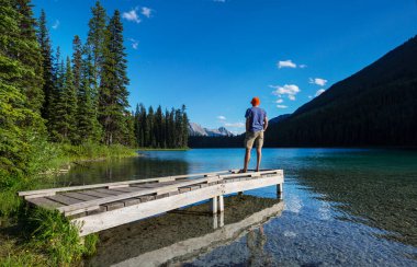 Bir adam sakin gölün yanında dinleniyor. Rahatlama tatili