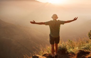 Bir turist, dağlık arazileri gözetliyor.