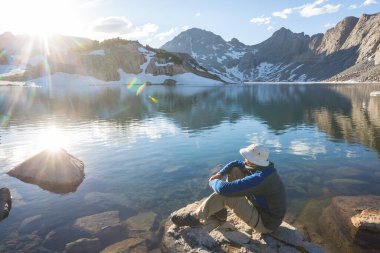Bir adam sakin gölün yanında dinleniyor. Rahatlama tatili