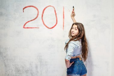 Kız bir Noel dekorasyonu duvar çizer..