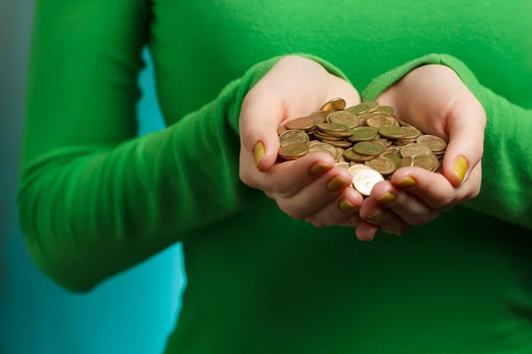 Дівчина в зеленому черепашці тримає золоті монети в руках — стокове фото