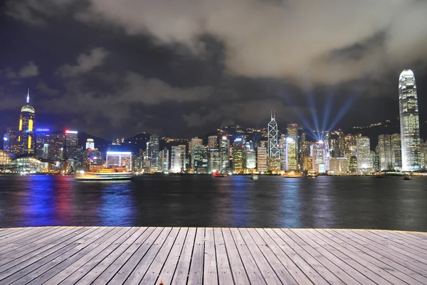 Hongkong cityscpae skyline por la noche, pavimento sendero de madera por el mar victoria . — Foto de Stock