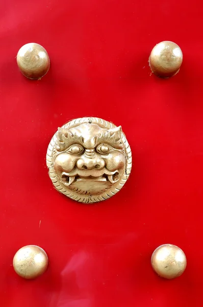 A cabeça de leão de bronze chinês e a porta de madeira vermelha da cabeça do prego . — Fotografia de Stock